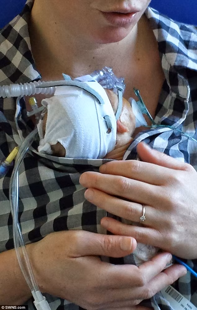 Ngày 25: Người mẹ ôm đứa con bé bỏng vào lòng để con có thể cảm nhận được hơi ấm và tình thương của mẹ. Đây là lần đầu tiên Shelley Court được ôm con từ khi sinh con.