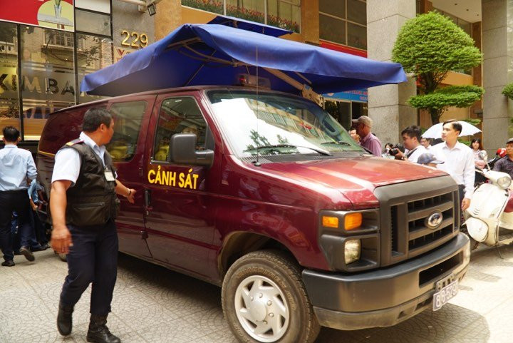 Quá trình điều tra, cơ quan công an xác định ông Lê Nguyễn Hưng và một số cá nhân khác có liên quan đến việc chiếm đoạt 245 tỷ đồng của bà Bình. Ông Hưng sau đó được xác định đã bỏ trốn ra nước ngoài, Bộ Công an đã phát lệnh truy nã quốc tế. Trong ảnh, xe cảnh sát lùi vào gần cửa ra vào Eximbank để áp giải hai nhân viên ngân hàng này. Nguồn ảnh: Vietnamnet