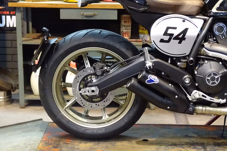 Ở hai bên thân xe, Scrambler Cafe Racer có 2 miếng nhôm in số 54 theo đúng phong cách những chiếc xe đua cổ điển. Số 54 mang ý nghĩa gợi nhớ về con số gắn liền với tay đua huyền thoại từng "đầu quân" cho Ducati là Bruno Spaggiari.