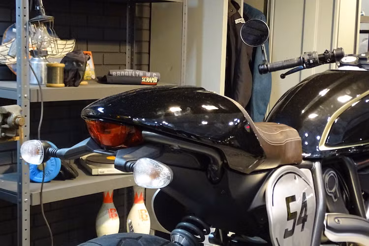 Ở phía sau, Scrambler Cafe Racer có phần đuôi khác biệt so với các phiên bản khác, với "gò" nhựa theo đúng phong cách cafe racer và yên solo bọc da, chần chỉ múi dọc đậm chất cổ điển.