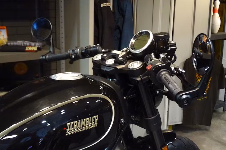 Theo đúng phong cách cafe racer, Scrambler Cafe Racer được trang bị cặp tay lái clip-on thể thao, với 2 đầu tay lái là cặp gương hậu gắn gù gọn gàng.