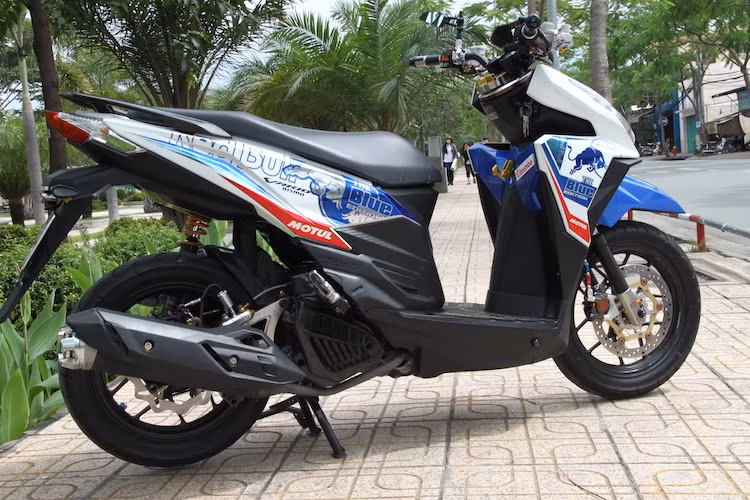 Để tăng thêm chất thể thao cho chiếc xe, dàn vỏ của bản độ Honda Click 125i đã được chủ nhân dán lên bộ tem đấu theo phong cách của đội đua RedBull tại nhiều giải đua trên Thế giới, với tông màu xanh-chrome-đỏ và trắng nổi bật.