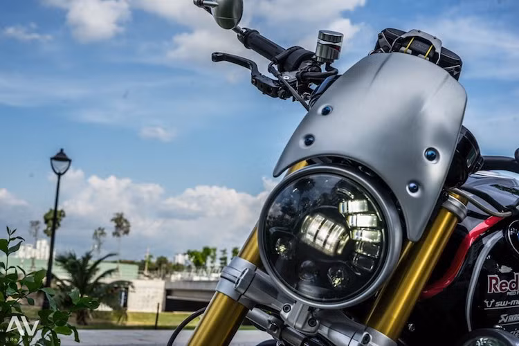Ở phía trên, phần đầu xe cũng đã được thay thế hoàn toàn với đèn pha LED "siêu ngầu" có chóa màu khói, không chỉ có công suất cao mà còn tiết kiệm điện hơn. Theo phong cách cafe racer, chiếc xe được trang bị kính chắn gió nhôm của Rizoma đặt ngay phía trên đèn pha.