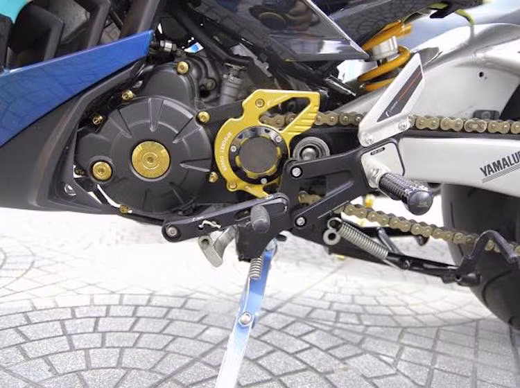 Khối động cơ nguyên bản của Exciter 135 đã được nâng công suất nhờ bộ lòng YCS trái 62 mm. Nắp mang cá chắn nhông là loại nhôm CNC của Rizoma. Chân chống bằng nhôm CNC cũng là một nét "chấm phá" độc đáo cho chiếc Exciter 135 độ này.