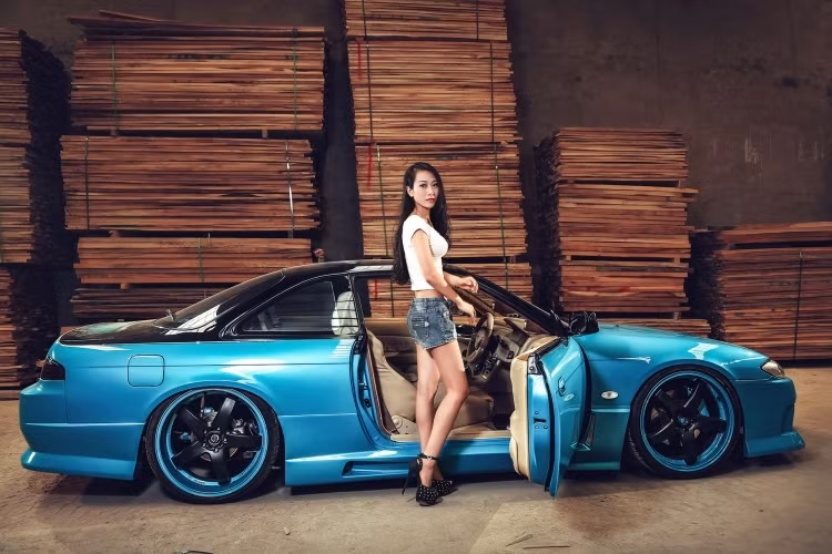 Chiếc Silvia đang cùng "so dáng" với mẫu nữ Trung Quốc này thuộc thế hệ thứ 6 của dòng xe với tên mã S14.Được giới thiệu tại Nhật Bản năm 1993, thế hệ S14 thấp và rộng hơn S13. Kiểu thiết kế thân xe với những đường nét cong tròn cho ta cảm giác như chiếc xe to hơn so với thực tế. Khoảng cách giữa hai trục bánh xe và bề rộng lốp cũng được tăng lên, đem lại khả năng vận hành ổn định hơn.