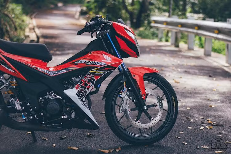 Ở phía trước, cặp phuộc nguyên bản của Sonic được giữ nguyên, nhưng đã có vỏ phuộc màu titan bắt mắt hơn. Hệ thống phanh trước của xe cũng đã được nâng cấp triệt để với heo Frando Racing 4 piston, đi kèm với đĩa phanh zin từ Sonic 150R và dây dầu Earl's.