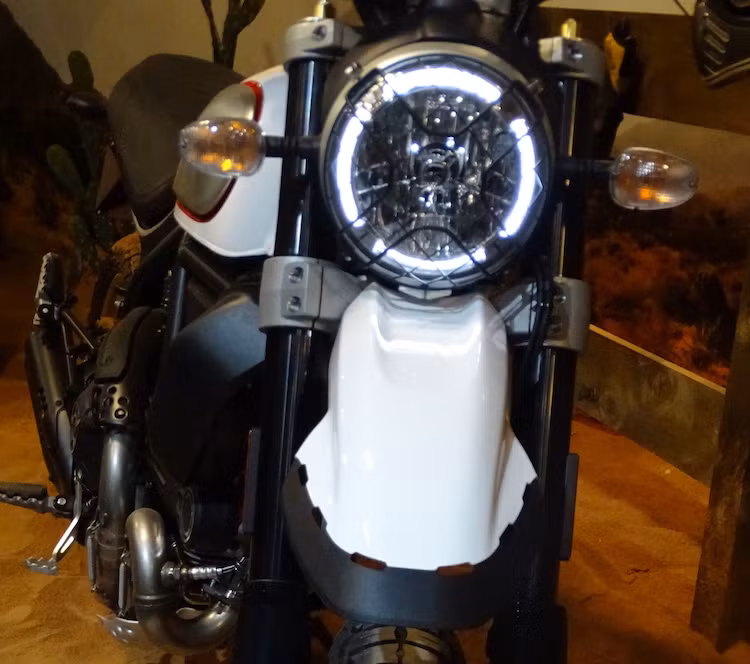 Ngay từ phía trước, Scrambler Desert Sled đã thể hiện rõ phong cách cực "bụi" của mình với đèn pha LED quen thuộc của dòng Scrambler được bảo vệ bởi một lưới thép cách điệu hình chữ X, ngay bên dưới là chắn bùn đặt cao theo đúng phong cách xe "cào cào".