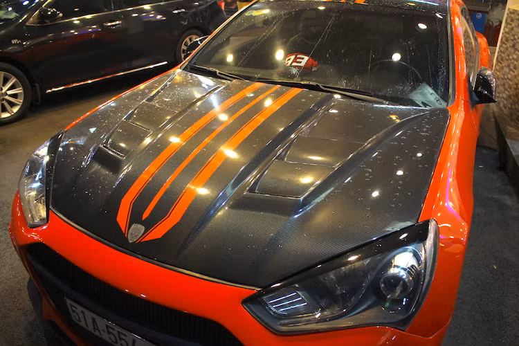 Nhìn vào đèn pha, có thể thấy rằng chiếc xe này thuộc phiên bản nâng cấp giữa vòng đời của Genesis Coupe, ra mắt lần đầu từ năm 2012. Nắp ca-pô của xe cũng đã được độ lại, được làm từ sợi carbon siêu nhẹ và "trổ" thêm các khe thoát nhiệt mới.