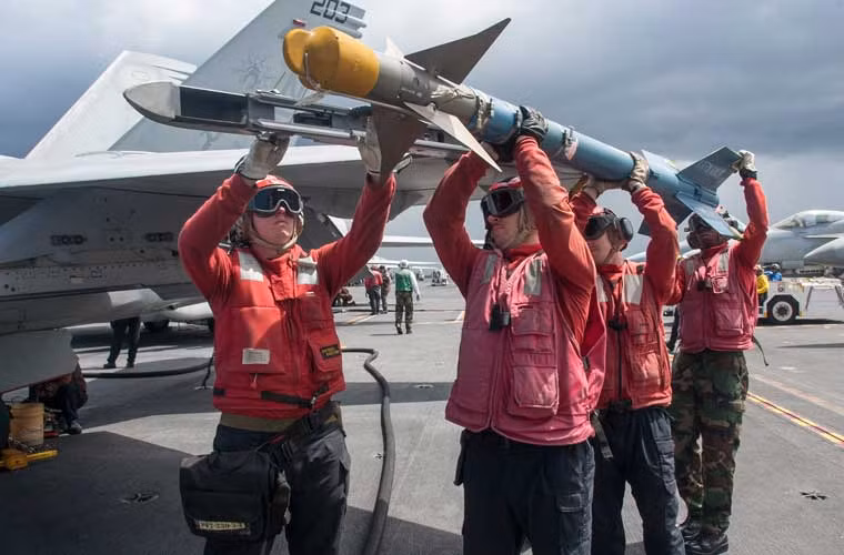 Cần bốn người đàn ông lực lưỡng mới lắp được quả đạn tên lửa AIM-9 lên cánh tiêm kích hạm F/A-18E trên tàu sân bay USS George Washington (CVN 73) hoạt động ở biển Philippine.