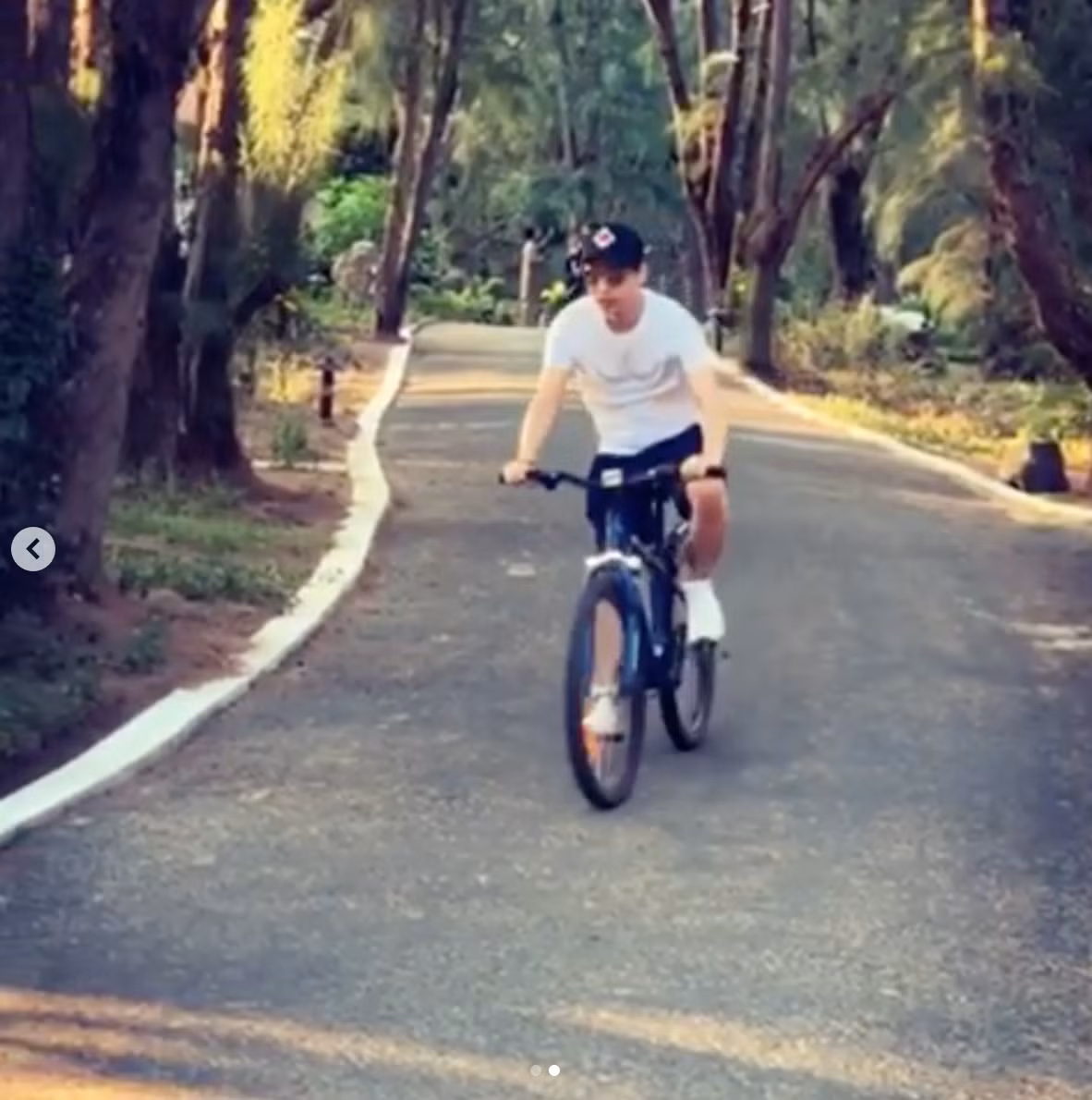 Hồ Quang Hiếu đăng clip đạp xe trên một con đường rợp bóng cây.