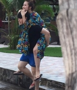 Nữ ca sĩ thích thú khi được bạn trai cõng trong chuyến du lịch biển.