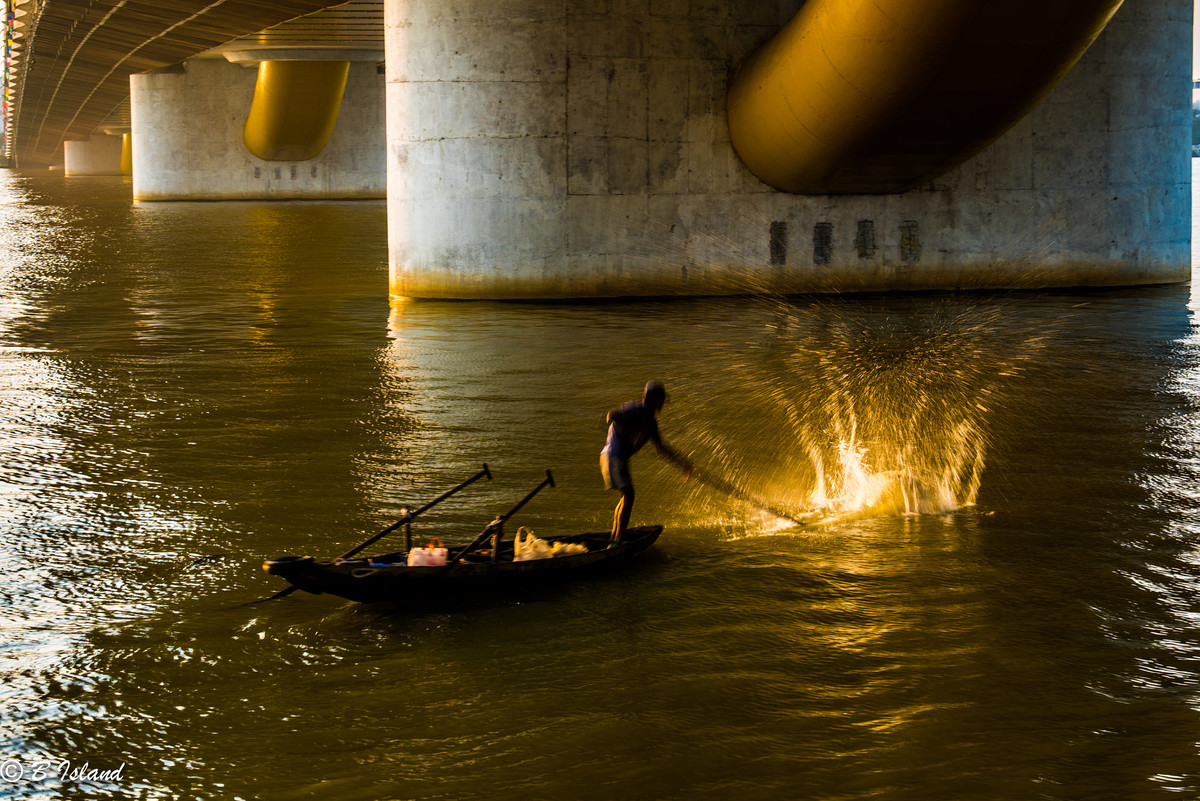 Người ngư dân mưu sinh dưới chân cầu Rồng Đà Nẵng. Ảnh: Manolin Santiago/ 500px.com.