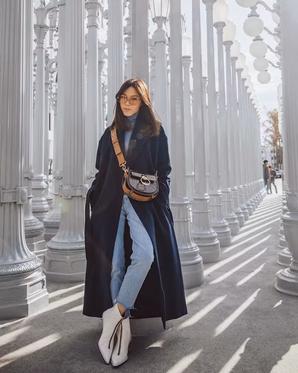 Khoác dáng dài mang hơi hướng cổ điển. Nếu chị em muốn set đồ tươi mới hơn có thể chọn trang phục màu xanh hải quân. Màu sắc này rất hiếm khi lỗi mốt, lại mang đến hiệu ứng thị giác vóc dáng thanh mảnh rất tốt.