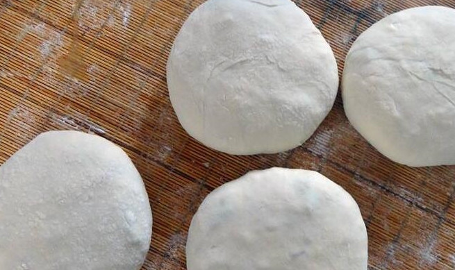 Giờ ta làm vỏ bánh và gói bánh. Cho một ít bột khô lên thớt, nhào lại bột, rồi chia nhỏ, lăn thành hình tròn, dẹt, cho nhân vào gói lại.