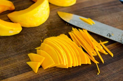 Bí đỏ sơ chế sạch và cắt bỏ phần đầu và đuôi sau đó cắt đôi quả bí ở giữa, lấy phần thịt bên trong, dùng dao thái thành sợi nhỏ, cho vào chậu rồi bổ đôi.