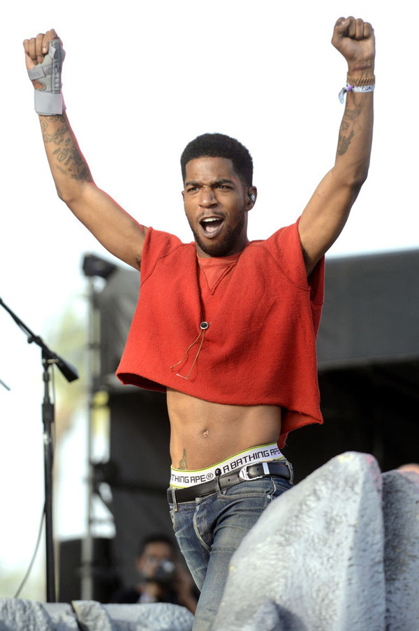 Trong hình, Kid Cudi biểu diễn trong chiếc áo crop top màu đỏ tại Coachella 2014.