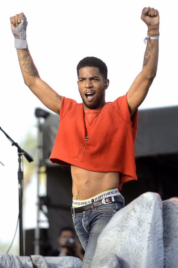 Trong hình, Kid Cudi biểu diễn trong chiếc áo crop top màu đỏ tại Coachella 2014.