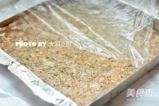 Phết một lớp dầu mỏng, dàn hỗn hợp ra khay nướng, phủ lớp màng bọc thực phẩm lên trên rồi cán mỏng ra thành tấm dầy 3mm.