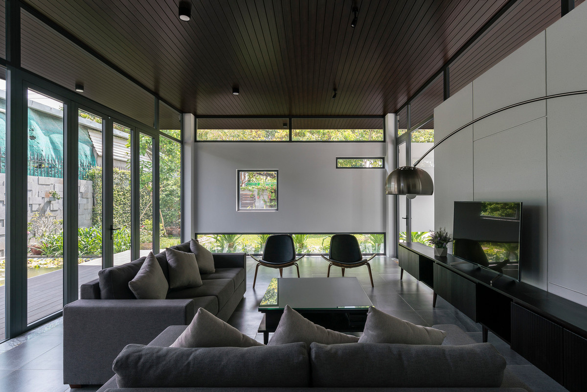 Phòng khách hướng ra khu vườn, với những góc cửa kính cắt khối hình học hiện đại.