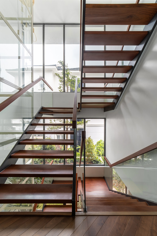 Bậc cầu thang thiết kế những khoảng hở kết hợp cùng lan can kính giúp ánh sáng len lỏi khắp căn nhà.