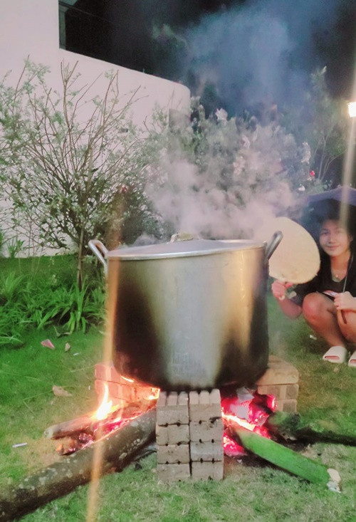 Vợ chồng nam diễn viên nấu bánh chưng ở sân vườn.