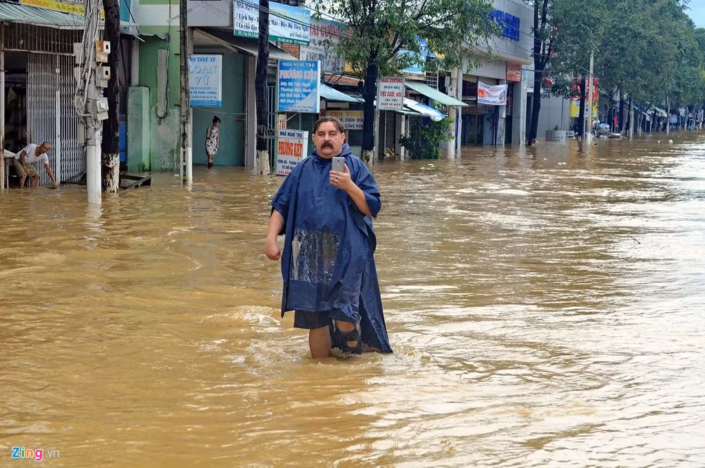 Một du khách người Nga mặc áo mưa lội bì bõm trên đường phố Nha Trang.