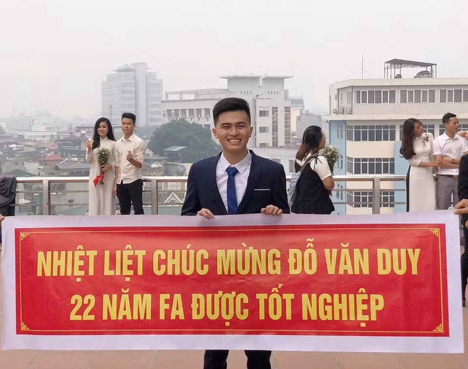 Để kỷ niệm ngày chuẩn bị tốt nghiệp, trong buổi chụp hình kỷ yếu, các bạn thân cùng phòng đã tâm lý chuẩn bị cho Văn Duy một tấm băng rôn với dòng chữ: “Nhiệt liệt chúc mừng Đỗ Văn Duy 22 năm FA được tốt nghiệp”. (Ảnh: Tổng hợp Facebook)