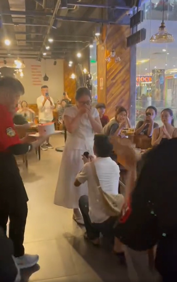 Đáp lại, chàng trai đã chủ động ôm bạn gái, quỳ xuống cầu hôn ngược lại bạn gái. Hành động tinh tế của người yêu khiến cô gái vô cùng xúc động, khách tại quán cũng rất bất ngờ.