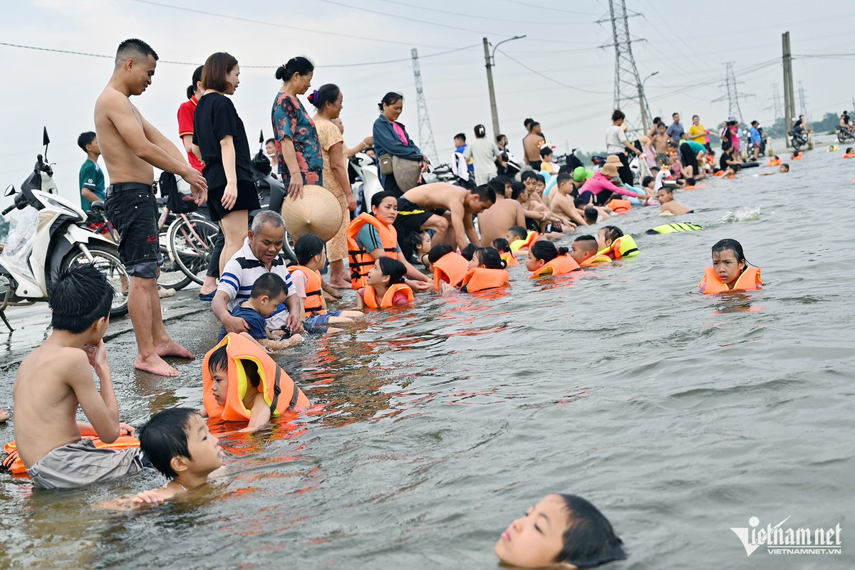 Đường dẫn vào làng đã thành "bể bơi", mọi người tập trung về khu vực này bởi không gian vừa rộng rãi vừa tiện để xe máy và trông nom trẻ nhỏ.