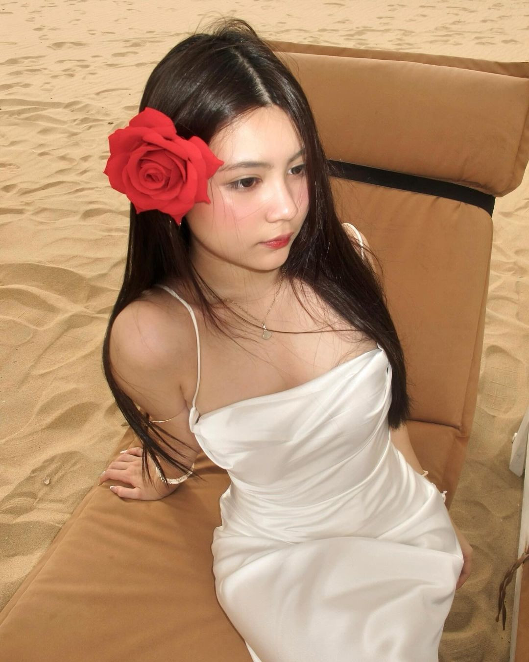 Cô nàng diện chiếc váy lụa màu trắng, khoe trọn đường cong cơ thể, kết hợp cùng bông hoa hồng cài lên tóc làm điểm nhấn.
