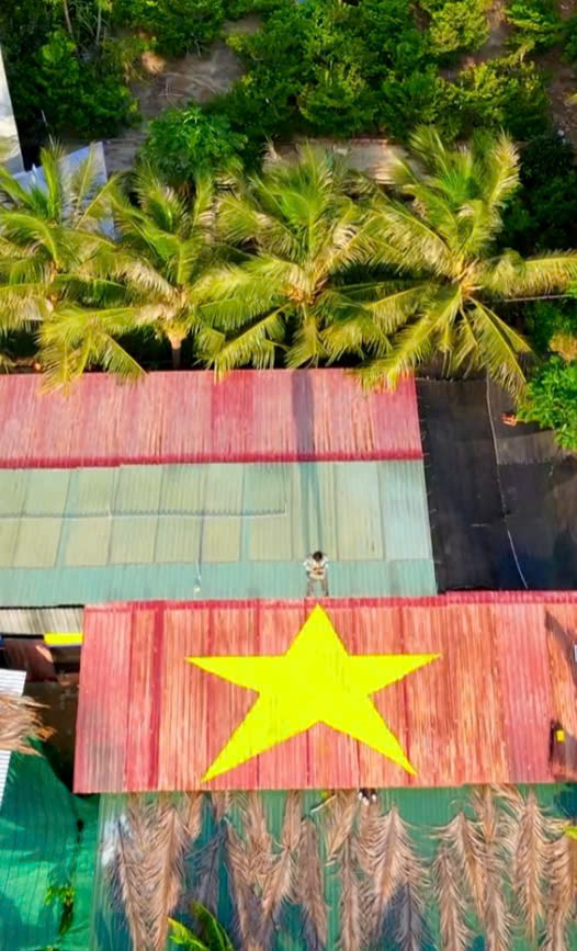 Anh Đinh Huy, ở Ninh Thuận, mất một tiếng dùng sơn vẽ cờ Tổ quốc lên mái nhà rộng 50m2, hôm 11/8. Sau khi đo đạc, dùng băng dính định hình khung ngôi sao vàng 5 cánh, anh pha sơn theo tỷ lệ, quét hai lớp để có được màu vàng ưng ý. (Ảnh: Tổng hợp Internet)