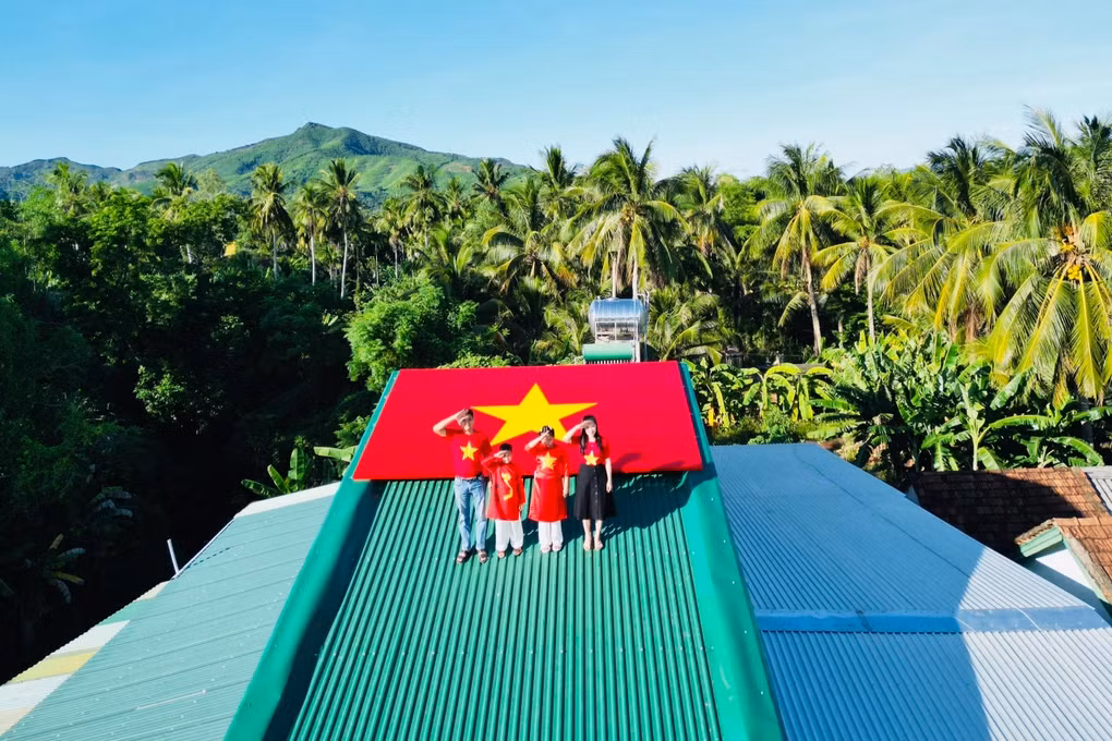 Sáng 13/8, gia đình 4 thành viên của chị Nguyễn Thị Thanh Tuyền (36 tuổi) mặc áo dài đỏ và áo cờ đỏ sao vàng, lên mái nhà chụp ảnh cùng lá cờ Tổ quốc đặc biệt.