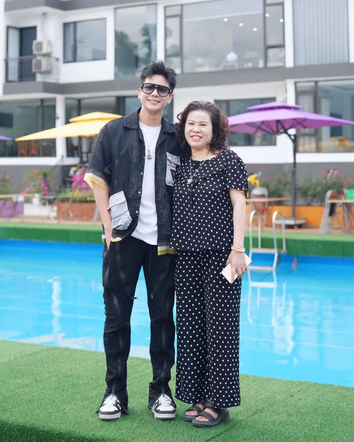 Khung cảnh phía sau Quân A.P và mẹ chính là khu villa của gia đình. Được biết, cơ ngơi này do mẹ anh quản lý.