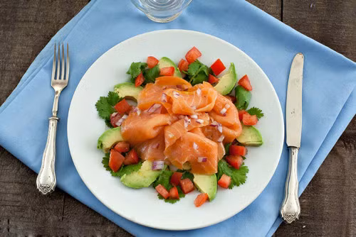 Salad cá hồi: Món này cực kỳ dễ thực hiện và giữ nguyên được hàm lượng dinh dưỡng của cá hồi. Để làm món này bạn cần chuẩn bị 30ml nước cốt chanh, 60ml dầu ô liu, 450g cá hồi hun khói, 2 quả bơ thái lát mỏng, 2 quả cà chua, một ít hành tây và rau mùi. Chỉ cần thái miếng và trộn tất cả các loại nguyên liệu kể trên là bạn đã hoàn thành món salad cá hồi. 