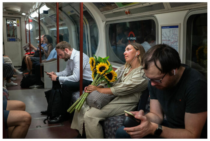 "Cô gái mơ mộng cầm bó hoa hướng dương trên tàu điện ngầm London (Anh), xung quanh là những hành khách hoàn toàn đắm chìm vào điện thoại thông minh của họ”, nhiếp ảnh gia Andrés Ramos chia sẻ về bức ảnh này.