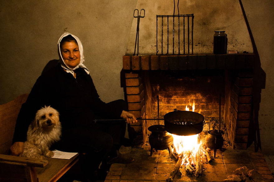 Một phụ nữ ngồi cạnh chú chó cưng của cô bên bếp lửa vào mùa đông.