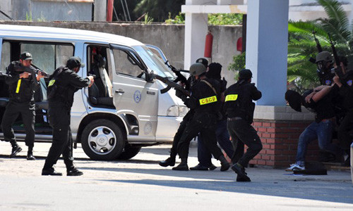 Cảnh sát áp giải nhóm khủng bố từ tòa nhà ra xe. 