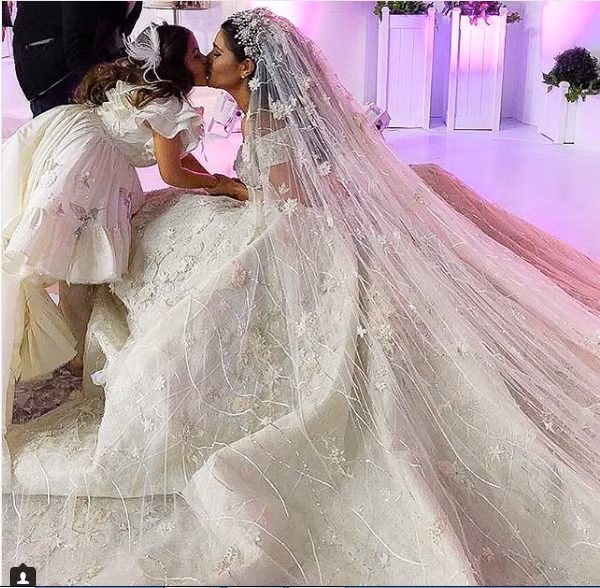 Cô dâu có hơn 117.000 người theo dõi trên Instargram, mặc một chiếc váy của nhà thiết kế Rami Kadi trong tiệc tiếp đón chính, chiếc váy được trang trí với những viên đá quý màu trắng và phần đuôi váy dài. Cô bé Mariam trong hình mặc váy thương hiệu Bibiona, một thương hiệu trời trang trẻ em cao cấp.