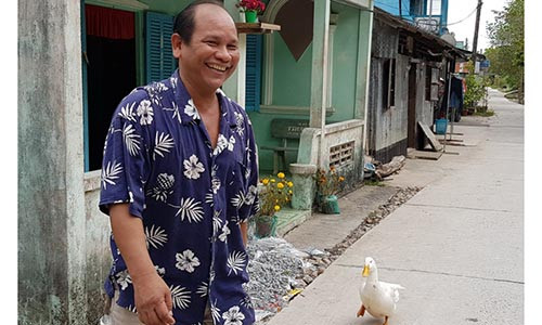 Ông Sơn Văn đi sang nhà hàng xóm thì chú vịt cũng lẽo đẽo theo sau. Ảnh: Việt Tường.