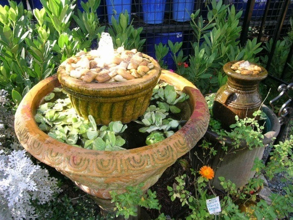 Hai chậu hoa được sử dụng làm thác nước nhỏ vô cùng tinh tế với vòi nước kết nối từ dưới lên trên. Một vài cây bèo tấm thả bên trong chậu to sẽ tạo nên vẻ đẹp yên bình cho khoảng sân vườn mùa hè.