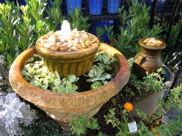 Hai chậu hoa được sử dụng làm thác nước nhỏ vô cùng tinh tế với vòi nước kết nối từ dưới lên trên. Một vài cây bèo tấm thả bên trong chậu to sẽ tạo nên vẻ đẹp yên bình cho khoảng sân vườn mùa hè.