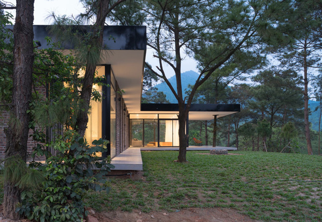 Nằm giữa một đồi thông tươi xanh mát mắt, căn nhà nhỏ 1 tầng thấp thoáng dưới những tán cây này là tổ ấm mơ ước của bất cứ gia đình nào. Tọa lạc trên đồi dốc, cả gia chủ và kiến trúc sư đều nhất trí rằng sẽ xây nhà “thuận theo tự nhiên”, tôn trọng thiên nhiên nên không san bằng khu đất để tạo nhiều diện tích xây dựng.