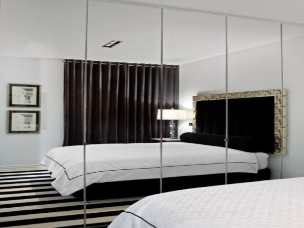 Gương được lắp đặt cho toàn bộ bức tường của phòng ngủ. Những tấm gương thay cho việc sơn tường có nhiệm vụ nhân đôi không gian một cách hiệu quả.