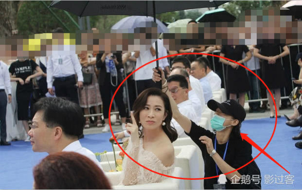 Trong khi trợ lý vất vả quỳ xuống che ô thì Xa Thi Mạn thản nhiên tạo dáng chụp ảnh.