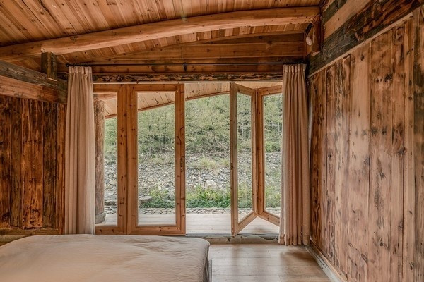 Tầng dưới gồm phòng khách, phòng ngủ và phòng tắm, được bao quanh bởi một sân lát đá. Cửa xếp dọc theo các phòng ngủ tạo ra các không gian mở nối các khu vực này thẳng ra ngoài vườn mang không khí trong lành vùng núi vào ngôi nhà.