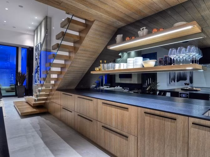 Tủ bếp bằng gỗ đặt dưới cầu thang được nhấn nhá bằng các loại đèn trang trí.