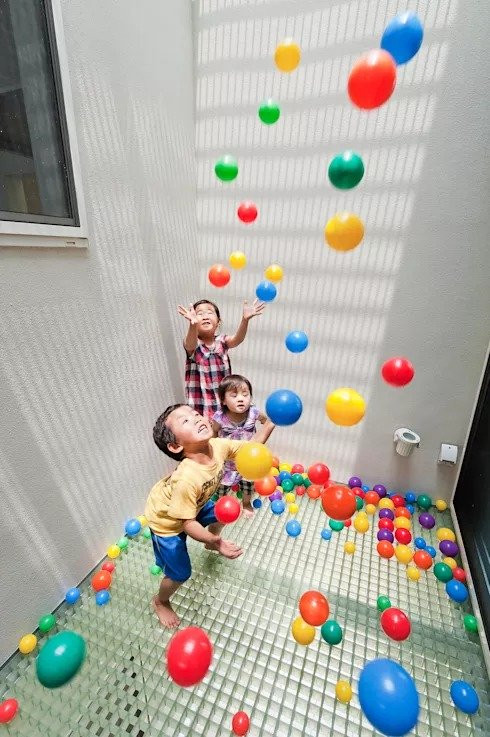 Tại đây, cả gia đình có thể thoải mái vui chơi, trò chuyện. Chiếc ghế sofa dài đặt sát tường vừa cung cấp nơi nghỉ chân thoải mái vừa đảm bảo nhà có đủ không gian trống để trẻ có thể tha hồ vui chơi. Và nếu tinh ý bạn có thể nhận thấy một điều bất ngờ tại góc trái của bức ảnh, đó là không cần đến khu vui chơi giải trí, trẻ hoàn toàn có thể vui đùa với những trái bóng tròn trong nhà bóng tại gia cực ấn tượng này. Sự vui tươi, nụ cười thích thú của trẻ, đó chính là mục đích của cha mẹ và cả các chuyên gia tìm kiếm khi thiết kế nên ngôi nhà đẹp này.