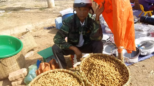 Người đàn ông chở lạc từ huyện Thuận Châu (Cách Tp.Sơn La hơn 40km) xuống khu chợ này với hi vọng sẽ bán được giá cao hơn 1 chút. Trời nắng nóng nhưng anh vẫn đội chiếc mũ bảo hiểm trên đầu và lấy tạm chiếc bao tải đựng lạc để làm “bình phong” che nắng.