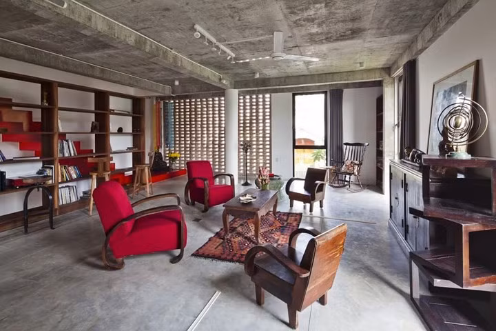 Ở tầng một, phòng khách và cầu thang luôn nhận được gió trời thông qua bức tường gạch xây mở.