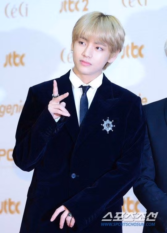 V, thành viên nhóm BTS nổi bật với mái tóc sáng màu. Anh thích thú tạo dáng trên thảm đỏ.